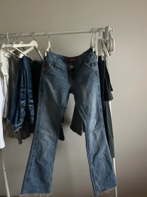Blå bootcut jeans  - Ett par klassiska blå bootcut jeans från Levi's med råa, fransiga benslut.Tillverkade i denim med en avslappnad passform.