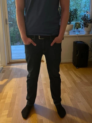 Svarta silm fit jeans - Säljer ett par svarta slim fit jeans med klassisk femficksdesign och bälteshällor. Jeansen har en stilren look och sitter tajt längs benen. Perfekta för dig som gillar en enkel och modern stil. Jag säljer jeansen för att jag vill byta stil. Storlek: 33-30. Pris kan diskuteras 