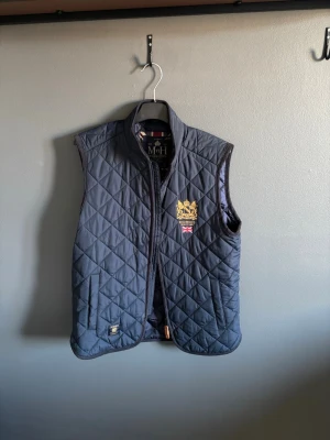 Mörkblå quiltad dunväst Morris - Blå quiltad dunväst från märket Morris. Den har inga defekter. Skick 9/10. Knappt använd. Storlek xs men passar som en small.