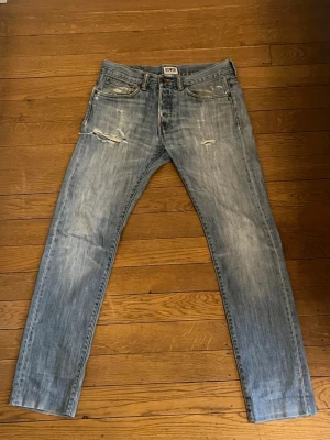 Edwin jeans - Ljusblå jeans från Edwin och slitna detaljer på framsidan. Klassisk femficksmodell med dragkedja och knapp. Priset är inte hugget i sten!