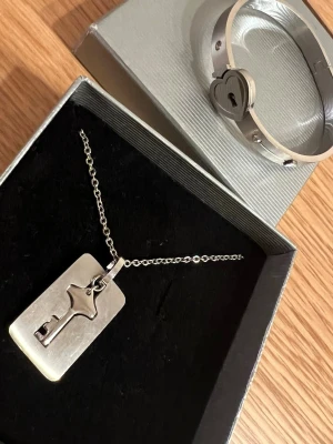 Armband och halsband i silver - Armband och halsband i silver; armbandet öppnas med nyckel. Lämplig för partners.
