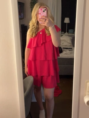 Rosa volang klänning - Säljer den här supersöta rosa klänningen! Det är en one shoulder klänning i volang, samma modell som zaras gula volang klänning fast denna är i rosa!  ❣️ KÖPT HÄR PÅ PLICK (andra bilden är sedan den tidigare annonsen)!! och säljer den nu då den inte kommer till användning (endast använd en gång) 🩷  🎀 Storlek M men passar mig bra som vanligtvis har storlek S/XS