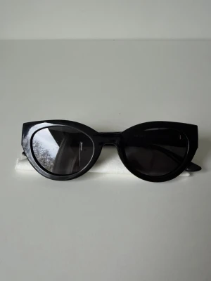 Svarta cat eye solglasögon Pilgrim - Snygga svarta cat eye solglasögon från Pilgrim med glansig finish och markerad båge. Glasögonen har en klassisk och trendig form som ger en cool vibe till din stil. Perfekta för att lyfta vilken outfit som helst 🤍