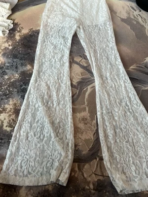 Vita spetsleggings  - Säljer ett par vita utsvängda leggings från SHEIN i storlek XS. Leggingsen är i genombruten spets med blommönster och har resår i midjan. Perfekta för dig som vill ha en unik och trendig look med extra detaljer.