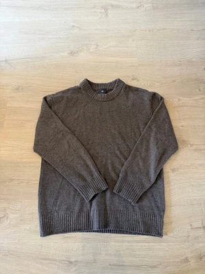 Brun stickad tröja från H&M - En enkel och stilren brun stickad tröja från H&M med rund halsringning och ribbade muddar vid ärmslut och nederkant. Perfekt för lager-på-lager och passar till jeans eller chinos. Materialet är mjukt och behagligt.