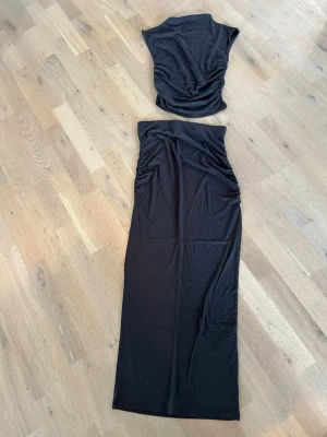 Duvblått tvådelat set med drapering, från Gina Tricot - Snyggt duvblått tvådelat set med crop top och lång kjol., frp. Gina Tricot. Toppen har draperade detaljer på sidorna och är ärmlös med rund halsringning. Kjolen är lång och rak med matchande drapering. Mjukt och stretchigt material, perfekt för en trendig look. Aldrig använt, helt nytt💖! 