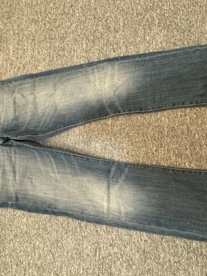 Blå Replay jeans med slitningar - Snygga blå jeans från Replay med klassiska slitningar och ljusare partier på låren. Jeansen har raka ben och detaljerade sömmar vid fickorna. Perfekta för en avslappnad och trendig look.