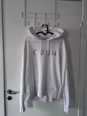 Vit hoodie från HUGO med tryck - Säljer en clean vit hoodie från HUGO med silverfärgat tryck på bröstet. Hoodien har en stor huva med ribbade ärmar och nederkant. Perfekt för dig som gillar minimalistisk och stilren streetwear.