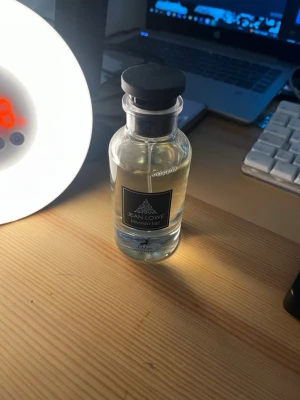 Jean Lowe Immortel parfymflaska - Stilren parfymflaska från Jean Lowe med svart lock och genomskinligt glas. Flaskan har en modern, minimalistisk design och etikett med texten 'Immortel'. Perfekt för dig som gillar eleganta och tidlösa dofter.