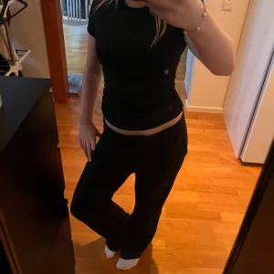 Lågmidjade kostymbyxor  - Svarta kostymbyxor med rak och lite loose passform, klassisk midja och bälteshällor. Byxorna har en enkel design utan synliga detaljer och är perfekta för en clean look. Materialet känns som polyester eller bomull, och de har fickor på sidorna. Skicka pm vid funderingar🙌🏻😊