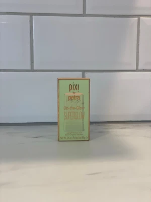 Pixi On-the-Glow SuperGlow highlighter - Highlighter i stickform från Pixi by Petra, On-the-Glow SuperGlow. Kommer i en mintgrön förpackning med guldiga detaljer. Perfekt för att ge huden en fräsch och strålande lyster. Enkel att applicera direkt på huden.