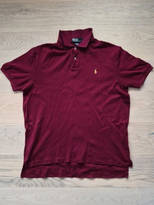 Vinröd pikétröja från Polo Ralph Lauren - Vinröd Ralph Lauren Pikétröja. I storlek L. I fint skick.  Axelbredd: 53cm Längd: 74cm