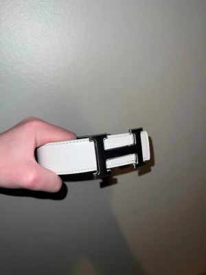Vitt läderbälte med H-spänne - Helt nytt vitt bälte, går även att byta sida till svart om man skulle gilla det mer. Hör av er vid intresse. Priset går att diskutera.