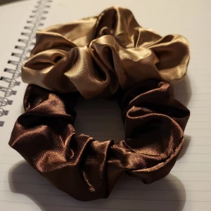2 Satin scrunchies. - “Elegant set med satin-scrunchies i mjuka mokkainspirerade neutrala toner. Hårsnoddar i mokkabrunt, beige och varma jordfärger som ger en stilren och sofistikerad look. Mångsidiga håraccessoarer för kvinnor – perfekta för både vardag och fest.”