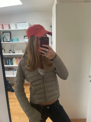 Vårjacka dam - Säljer en grå/beige, pufferjacka från H&M med diskret rund krage och knäppning framtill. Jackan har ett quiltat mönster och är tillverkad i ett lätt, syntetiskt material som håller värmen. Perfekt för våren och sommaren och enkel att matcha med olika outfits. Har tappat en knapp längst nere men det är inget som syns tydligt. Tar emot prisförslag!!!