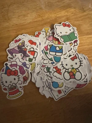 Hello Kitty klistermärken mix 100st - Ca 100st färgglada Hello Kitty klistermärken i olika motiv och former. Perfekta för att dekorera dator, mobil, anteckningsbok eller vad du vill. Motiven visar Hello Kitty i olika outfits och aktiviteter. Materialet är papper med självhäftande baksida.