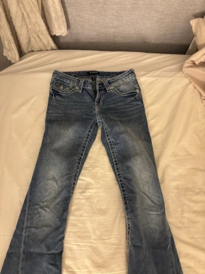 Blå bootcut jeans från True Religion - Säljer ett par blå bootcut jeans från True Religion med vita kontrastsömmar. Säljer för jag tröttnade på modellen och då inte använder något längre och inte kommer till användning. Nypris 1500 ungefär, priset kan diskuteras.