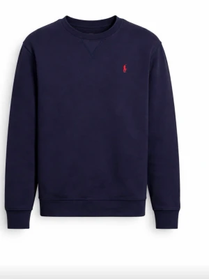 Mörk blå sweatshirt från Ralph lauren  -  MODELLEN ÄR 173 cm lång  sweatshirt från Ralph Lauren med klassisk rundhalsringning och den ikoniska röda logotypen broderad på bröstet. Tröjan har långa ärmar och ribbade muddar vid ärmslut och nederkant. Perfekt för en avslappnad och stilren look. 