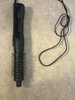 Svart varmluftsborste med sladd - En svart varmluftsborste med rund borste och sladd. Perfekt för att styla håret och skapa volym. Handtaget är i plast och borstdelen har täta piggar i plast. Passar dig som vill fixa frisyren snabbt och enkelt hemma.