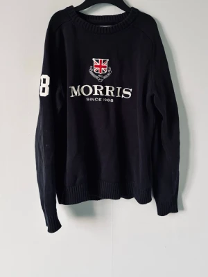 Navy tröja från Morris - Snygg mörkblå stickad tröja från Morris med broderad logga och brittisk flagga på bröstet. Tröjan har rund halsringning och ribbade muddar vid ärmslut och nederkant. Strl M men passar mer S. Mycket bra skick och nypris ca 1200 kr.Pris går att diskutera!✌️ 