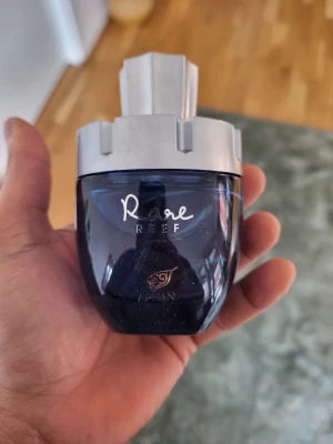 Rare Reef parfym från Armaf 100ml - Rare Reef Extrait De Parfum från Armaf i en cool, mörkblå flaska med silverfärgat lock. Flaskan rymmer 100 ml och har en modern, robust design som sticker ut i badrumshyllan. Perfekt för dig som gillar unika och fräscha dofter.