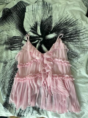 Rosa volangig linnetopp med ränder - Supersöt rosa linnetopp med tunna axelband och volanger i flera lager från Amisu. Endast använd ett fåtal gånger. I storlek XL men passar även S. Perfekt för sommaren.