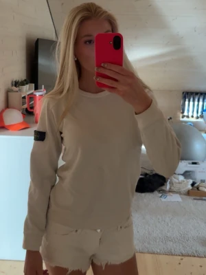 Vit långärmad topp från Stone Island - Vit långärmad topp från Stone Island med klassisk rund halsringning och logotyp-patch på vänster ärm. Enkel och stilren design som passar perfekt till jeans eller shorts. Junior size, fits like a S