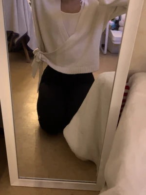 Vit omlottkofta med knytband - Snygg vit omlottkofta med knytband i sidan och ribbade muddar. Koftan har en avslappnad passform och är perfekt att slänga över ett linne. Mjuk och skön, passar till många olika outfits.