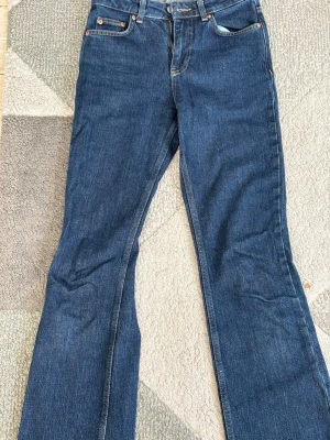 Mörkblå raka jeans - Snygga mörkblå raka jeans i klassisk modell med fickor och midwaist. Jeansen har raka ben som blir lite vidare nedtill och är tillverkade i denim. Perfekta för en avslappnad och trendig look.
