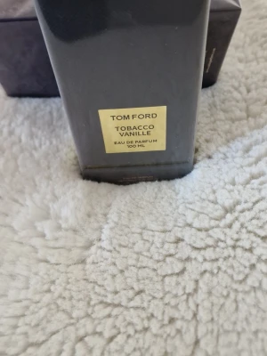 Tom Ford Tobacco Vanille 100 ml parfym - Tom Ford Tobacco Vanille Eau de Parfum 100 ml. Flaskan är svart med guldiga detaljer och har en lyxig, stilren design. En ikonisk doft med inslag av tobak och vanilj, perfekt för dig som gillar exklusiva parfymer.
