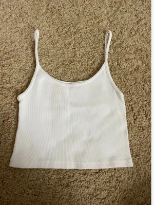 Vit ribbad linnetopp - Snygg vit ribbad linnetopp med smala axelband och croppad passform. Perfekt att matcha med jeans eller kjol för en trendig look. Enkel och stilren design som passar till många outfits. Från Brandy Melville
