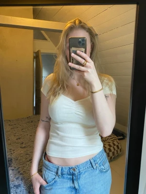 Vit croppad topp med v-ringning - Vit T-shirt ifrån Gina Tricot. Använd ett fåtal gånger, inga tydliga tecken på användning.