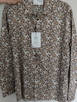 Blommig skjorta från Selected Homme - Långärmad skjorta från Selected Homme med blommigt mönster i brunt, beige och vitt. Skjortan har klassisk krage, knäppning framtill och är tillverkad i mjuk bomull. Skjortan är helt oanvänd. 