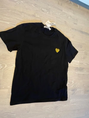 Svart t-shirt från Comme des Garçons Play - Tja! Säljer en fet. Svart t-shirt från Comme des Garçons Play med det ikoniska gula hjärtat med ögon broderat på bröstet. Storleken är M men skulle passa S också ( mått finns ). Priset kan diskuteras och skickar inom 24 Tim ☺️💨