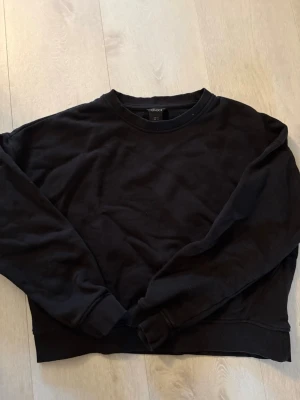 Svart sweatshirt  - En klassisk svart sweatshirt med rund halsringning och långa ärmar. Tröjan har ribbade muddar vid ärmslut och nederkant. Mindre i storleken.
