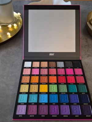 BRIGHT ögonskuggspalett med spegel - Stor ögonskuggspalett från Beauty Bay med 42 färgstarka nyanser i både matta och skimrande finish. Paletten innehåller allt från neonrosa, blått, grönt, lila till neutrala toner. Praktisk spegel i locket och rektangulära pans. Perfekt för kreativa sminkningar. Ny palett. Ser helt orörd ut. Men säger eventuellt swachad. Mycket fin palett