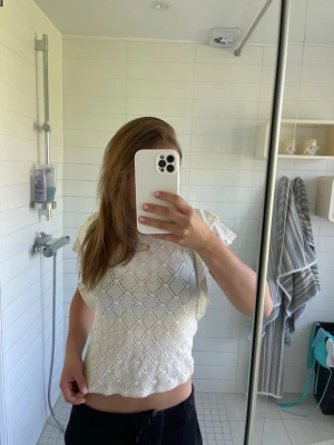 Vit spetsig croppad topp Gina Tricot - Supersöt vit blus från Lindex med korta volangärmar och snyggt mönstrad struktur. Blusen har rund halsringning och knäppning bak i nacken. Perfekt till jeans eller kjol för en fräsch look.
