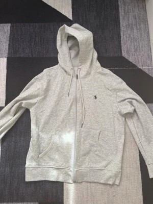 Grå zip-hoodie från Polo Ralph Lauren - Snygg ljusgrå hoodie med dragkedja från Polo Ralph Lauren. Pris kan diskuteras 