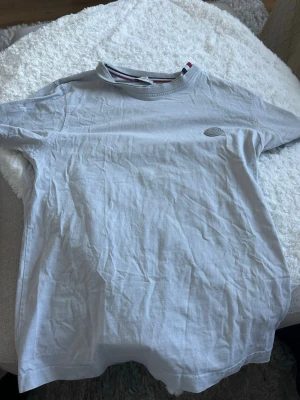 Grå Moncler t-shirt med logga - Snygg grå t-shirt från Moncler med diskret logga på bröstet och klassisk rund halsringning med röd, vit och blå detalj på insidan. Tillverkad i mjuk bomull och har en normal passform. Perfekt för en clean och stilren look.