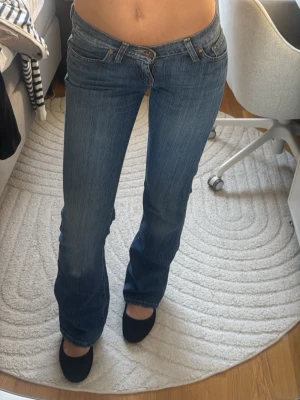 Blå bootcut jeans från G- star - Säljer ett par klassiska blå bootcut jeans från True Religion med låg midja och snygga detaljerade bakfickor. Jeansen har en lätt tvättad look och är tillverkade i stretchigt denim för en bekväm passform. De är storlek XS och passar mkg perfekt som är 169,5 och även bär XS