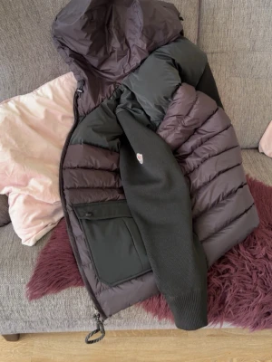 Svart Moncler dunjacka med huva - Säljer en svart dunjacka från Moncler med huva och stickade ärmar. Jackan har två stora fickor framtill och klassisk Moncler-logga på ena ärmen. Perfekt för kalla vinterdagar och riktigt snygg streetstil.   Helt svart jacka,cardigan solen skiner på den så den ser ut inte svart men det är helt svart .pris kan diskuteras 