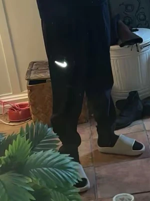Svarta Nike Miller mjukisbyxor med logga - Svarta mjukisbyxor från Nike med klassisk vit Swoosh-logga på låret. Byxorna har resår i midjan och vid bensluten för en skön passform. Perfekta för chill eller träning, tillverkade i mjukt material.