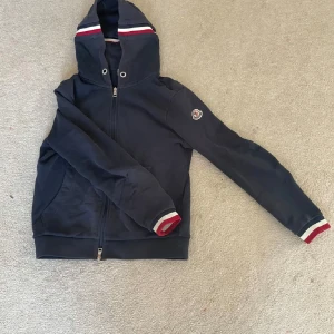 Moncler zip hoodie - Riktigt snygg moncler zip hoodie i storlek S. Inga större defekter men lite smått urtvättad och har jättesmå hål i ärmen!