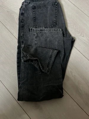 Svarta loose fit jeans - Säljer ett par svarta loose fit jeans i tvättad denim med hög midja och raka ben. Jeansen har klassiska bakfickor och en avslappnad passform. Perfekta för en chill och trendig look.