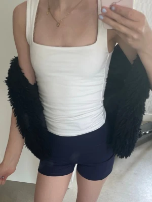 Svart fluffig pälsväst - Säljer en svart, fluffig pälsväst med öppen front och mjuk, lurvig struktur. Västen har en rak passform och är perfekt för att addera lite edge till din outfit. Märke och material är okänt men den känns riktigt mysig och trendig.