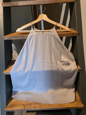 Ljusgrå ärmlös linnetopp från H&M - Säljer en stilren ljusgrå linnetopp med tunna axelband och rak halsringning. Toppen har en lös passform och är perfekt för varma dagar. Enkel och clean design som passar till mycket. Strl M