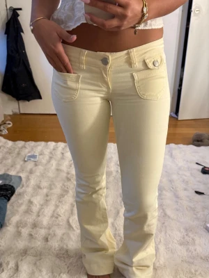 Ljusgula bootcut jeans - Snygga ljusgula jeans med bootcut-modell och låg midja. Jeansen har fram- och bakfickor samt knapp- och dragkedjestängning. 