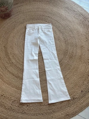 Vita jeans Gina tricot  - Säljer ett par vita jeans med utsvängda ben och klassisk femficksmodell. Jeansen har hög midja och är sydda i ett stretchigt denimtyg för skön passform. Perfekta för dig som gillar retrovibbar och vill sticka ut lite extra.
