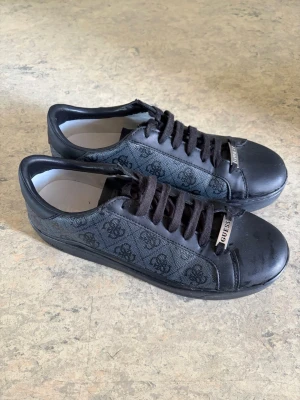 Guess Sneakers – Svarta – Storlek 40,5 - Säljer ett par svarta Guess sneakers i storlek 40,5. Använda några gånger, men fortfarande i bra skick med endast lätta bruksspår. Inga skador eller defekter.  ✔️ Storlek 40,5 ✔️ Färg: Svart ✔️ Använda få gånger ✔️ Bekväma och stilrena ✔️ Passar både vardag och streetwear 
