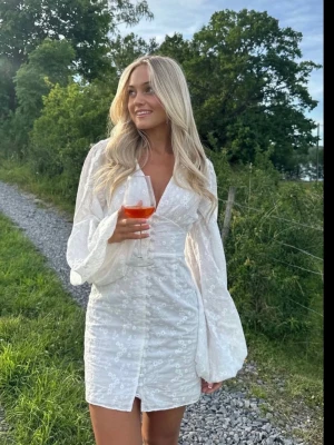 Helt ny adoore klänning! - Säljer en vit kortklänning med blommigt mönster och v-ringad hals. Klänningen har långa, luftiga ärmar. Perfekt för sommarens alla tillfällen. Passformen är normal och materialet känns lätt och bekvämt. Endast testad, säljer pågrund av att jag inte använt den (nypris 1500) 💓